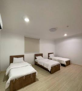 Zimmer mit 2 Betten und einer weißen Wand in der Unterkunft شاليهات الود in Abha