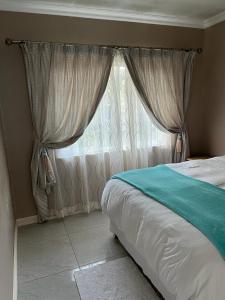 a bedroom with a bed and a window at White House lodge in Scotburgh in Scottburgh