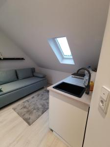 eine Küche mit einem Waschbecken und einem Sofa in einem Zimmer in der Unterkunft Dachzimmer mit Kochecke und Duschbad, nahe Messe in Hannover
