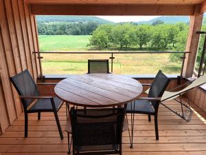 una mesa de madera y sillas en un porche con vistas en Le Séchoir des acacias, Gite: Les Falaises, en Saint-Léon-sur-Vézère