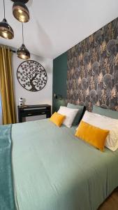 Un dormitorio con una gran cama verde con almohadas amarillas en Chambre d'hôte chez Roberto et Hervé, en Puilboreau
