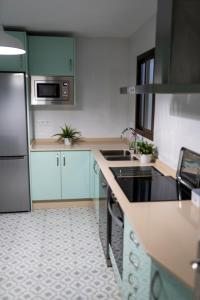 Una cocina con gabinetes verdes y una estufa. horno superior en Casa Hacha, en Corteconcepción