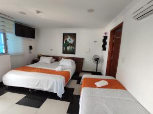 a hotel room with two beds and a television at Apartamento Villa llano in Villavicencio