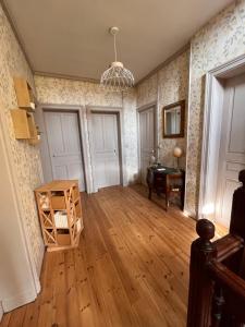 ein Wohnzimmer mit Holzboden und einem Kronleuchter in der Unterkunft Vers le soleil levant in Croisilles