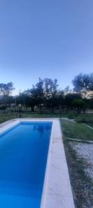 a blue swimming pool with trees in the background at Casa V.Giardino pileta y cochera in Villa Giardino