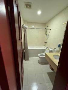 a bathroom with a toilet and a tub and a sink at Zolotoi Drakon Hotel in Almaty