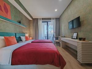 a bedroom with a bed and a desk and a television at Round Garden Hotel in Tbilisi City