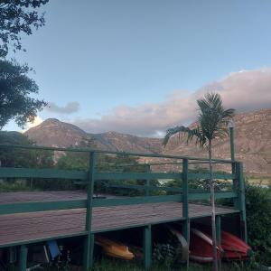 um banco com uma palmeira e montanhas ao fundo em Casas e apartamentos da Praia, Lapinha na beira do lago em Santana do Riacho