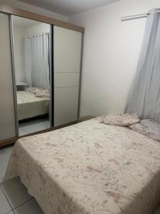 ein Schlafzimmer mit einem Bett und einem großen Spiegel in der Unterkunft Apartamento grande próximo da praia do calhau in São Luís