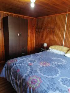 a bedroom with a bed with a blue blanket at Cabañas Roma in Valdivia