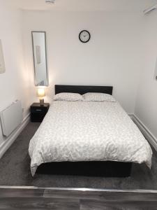 a bedroom with a bed and a clock on the wall at NOIR COLLECTIVE #2 188 MARSH ROAD in Luton