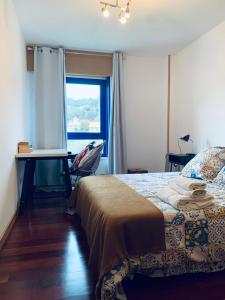 um quarto com uma cama, uma secretária e uma janela em Apartamento exclusivo con vistas al mar em Outes