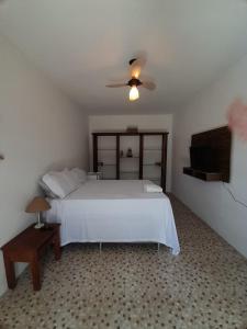 um quarto com uma cama branca e uma televisão em Suites na Vila em Maraú