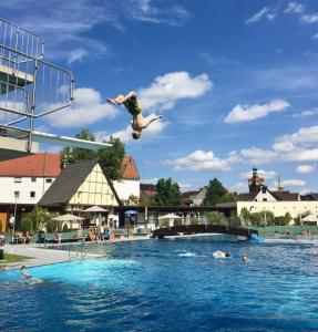a person jumping into a swimming pool at Riverview Loft in Central Herzogenaurach in Herzogenaurach