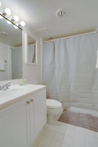 Baño blanco con aseo y lavamanos en Quiet Apt with Excellent Amenities @Crystal City, en Arlington