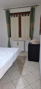 1 dormitorio con cama blanca y cortinas verdes en Bilocale via Rimini 5C, en Pomezia