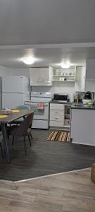 uma cozinha com armários brancos, uma mesa e uma sala de jantar em Le Cent Onze em Gatineau