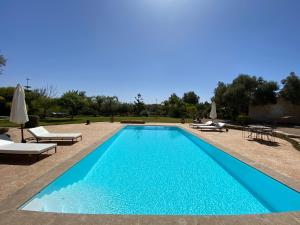 una piscina blu con sedie a sdraio e ombrelloni di Dar Luce a Essaouira