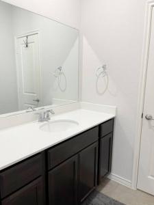 ein Badezimmer mit einem Waschbecken und einem großen Spiegel in der Unterkunft Family Perfect Vacation Home in McKinney