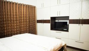 a bedroom with a bed and a tv and cabinets at Urban Oasis Homestay: AC Bedrooms in Trichūr
