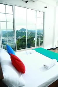 ein Schlafzimmer mit einem weißen Bett mit roten und blauen Kissen in der Unterkunft Eden Rock Luxurious Accommodation in Kandy