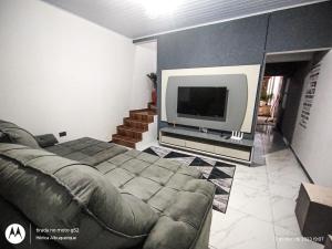 uma sala de estar com um sofá e uma televisão de ecrã plano em Sobrado com piscina em Itanhaém