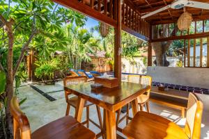 uma área de refeições exterior com uma mesa de madeira e cadeiras em Paradise Luxury Villa em Gili Air