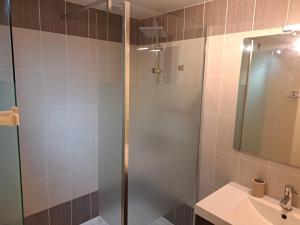 a shower with a glass door next to a sink at La Boussole in Étretat +4 photos