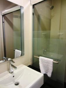 y baño con lavabo y ducha con espejo. en Grand Court Hotel, en Teluk Intan