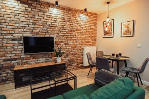 een woonkamer met een bakstenen muur en een flatscreen-tv bij LOFT Luxury Apartment & Parking in Leszno
