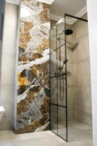 a shower in a bathroom with a stone wall at Apartament 6 Double Rest Jastrzębia Góra in Jastrzębia Góra