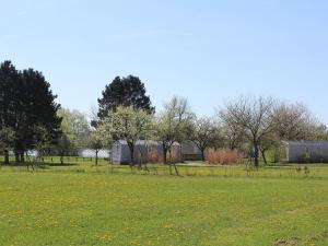 un champ d'herbe verte planté d'arbres et de bâtiments dans l'établissement Gîte Bures, 3 pièces, 4 personnes - FR-1-584-305, à Bures