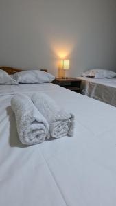 2 weiße Handtücher auf einem Bett liegen bereit. in der Unterkunft Hospedaje Latinos in Tarapoto