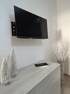 a tv hanging on a wall with two christmas trees at La Cupola - casa vacanze in Termini Imerese