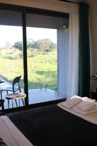 a bedroom with a bed and a large glass window at Zambujal Suites in Sesimbra