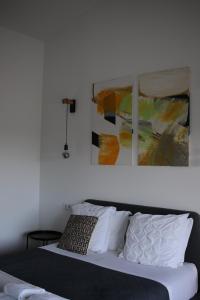 a bed with white pillows and a painting on the wall at Zambujal Suites in Sesimbra