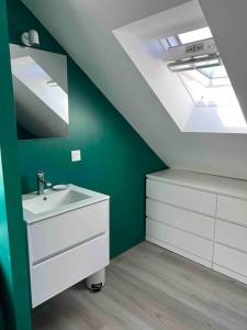 ein Badezimmer mit einem weißen Waschbecken und einer grünen Wand in der Unterkunft Maison en Baie du Mont St Michel in Le Val-Saint-Père