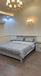 1 dormitorio con 1 cama grande y lámpara de araña en شاليه الشروق en Ash Shuqra
