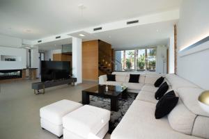 sala de estar con muebles blancos y TV de pantalla plana en Es Maiols Casa A en Can Furnet