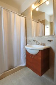 baño con lavabo y cortina de ducha blanca en AVIS Departamentos peatonal en Villa Carlos Paz