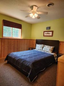a bedroom with a bed with a ceiling fan at Riverfront~On ATV Trials~Near Mackinac Island in Hessel