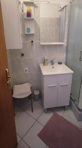 uma pequena casa de banho com um lavatório e uma cadeira em Jana apartman em Crikvenica