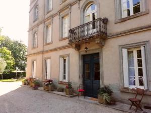 a building with a blue door and a balcony at Domaine de la Célarié in Mouzieys-Teulet