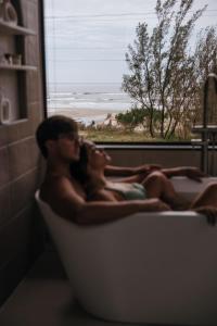 a man and a woman laying in a bath tub at O Chalé da Praia in Jaguaruna