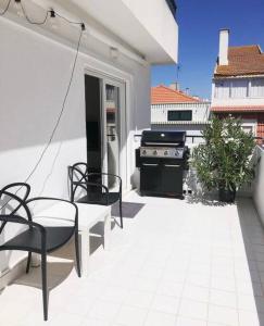 a patio with a stove and a table and chairs at Caparica Beach House in Costa da Caparica