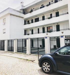 una macchina nera parcheggiata di fronte a un edificio di Caparica Beach House a Costa da Caparica