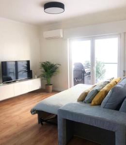 a living room with a couch and a tv at Caparica Beach House in Costa da Caparica