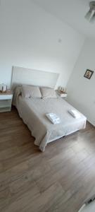 um quarto branco com uma cama e piso em madeira em Colores De La Quebrada em Cafayate