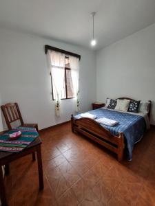 a bedroom with a bed and a chair and a window at A Lau' De Los Álamos in Humahuaca