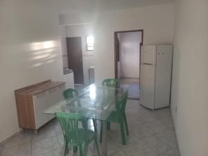 een keuken met een glazen tafel en groene stoelen bij Apartamento em Cabo Frio com Wi-fi in Cabo Frio